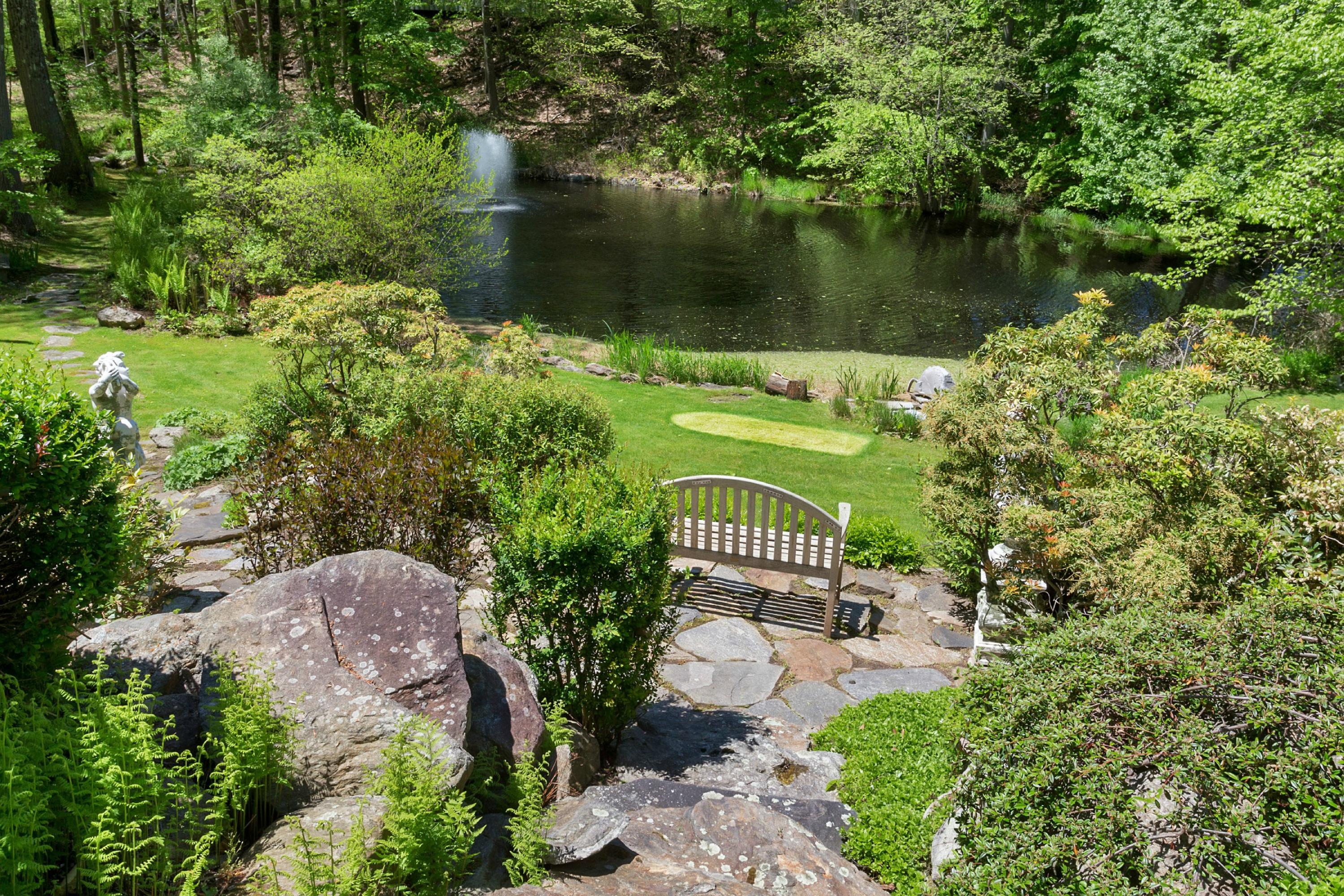 67 Sumner Road Greenwich, CT 06831 - Photo 21 of 25 a view of a lake with a bench under large trees