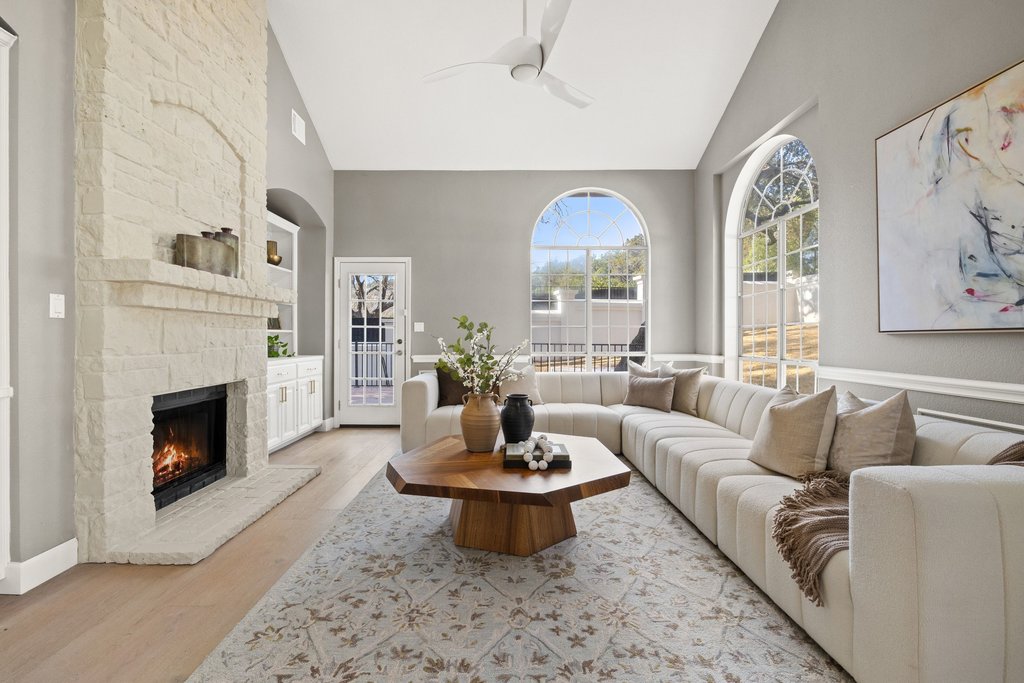 1815 Rue De St Tropez Austin, TX 78746 - Photo 3 of 39 Living room with a ceiling fan, lofted ceiling, light wood-style floors, a fireplace, and built in features
