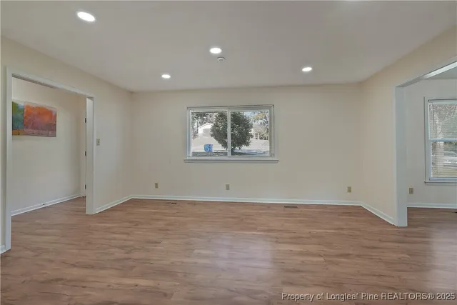 a view of an empty room with wooden floor and a window