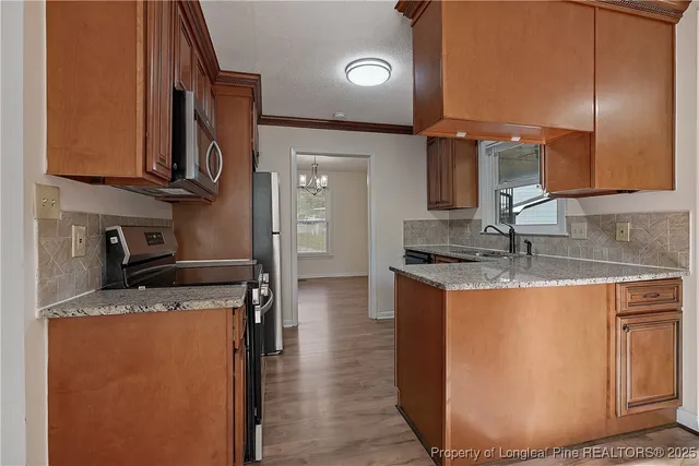 a kitchen with stainless steel appliances granite countertop a sink a stove and a refrigerator