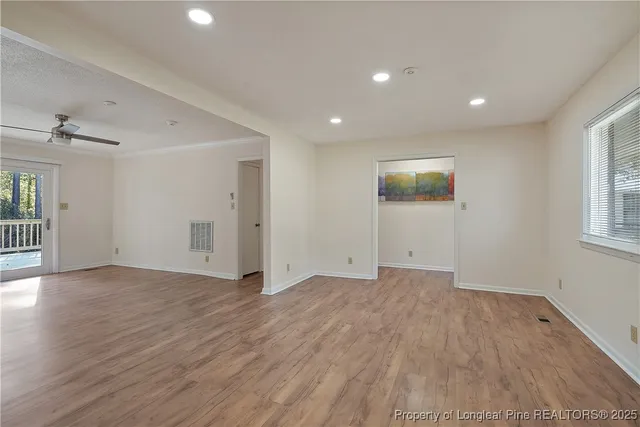 an empty room with wooden floor and windows