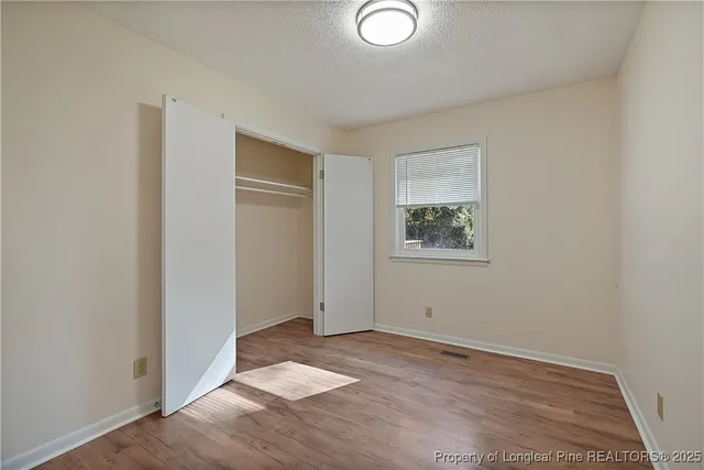 an empty room with wooden floor and window