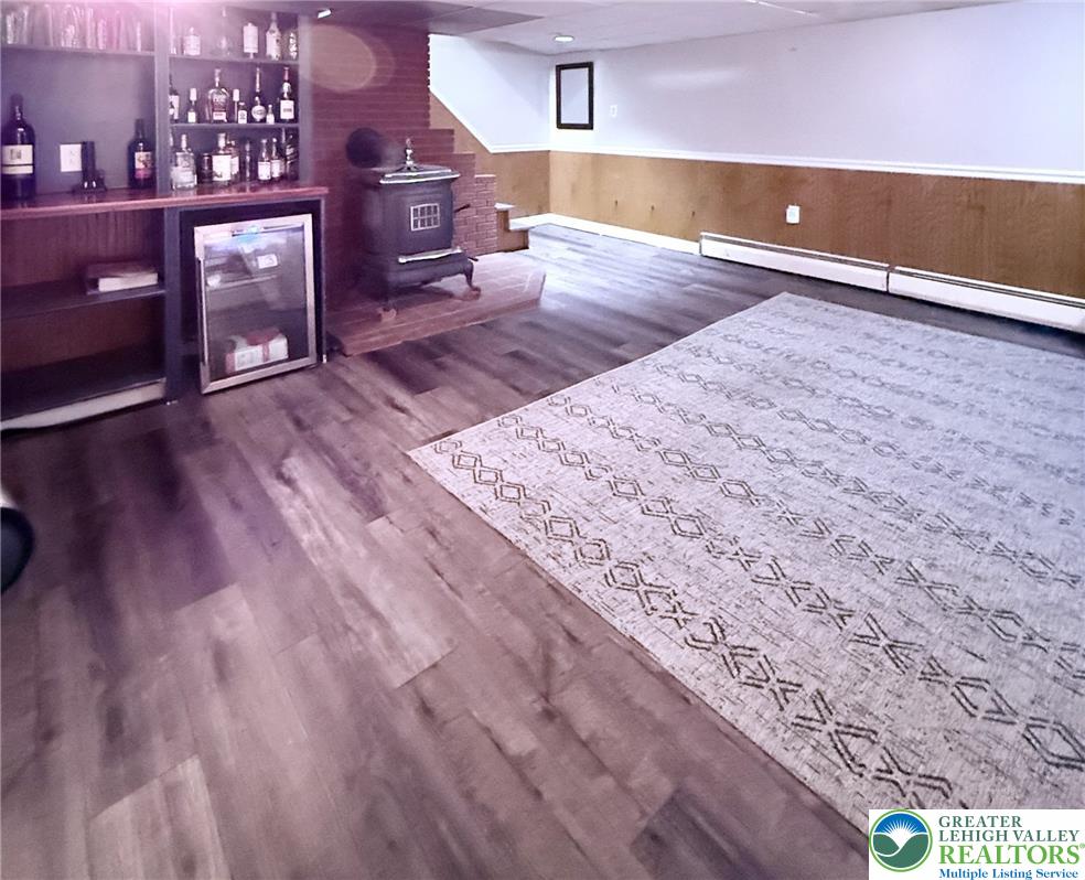 1275 Macada Road Bethlehem, PA 18017 - Photo 68 of 87 A well-appointed recreation room features a wet bar, warm wood flooring, and a classic wood-burning stove.