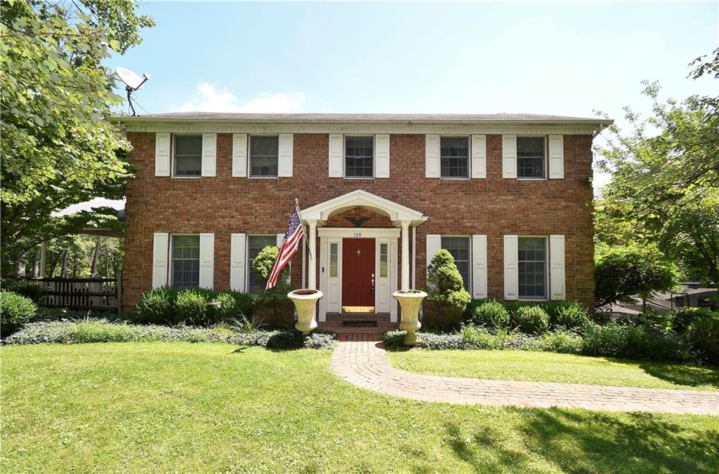 a front view of a house with yard and green space