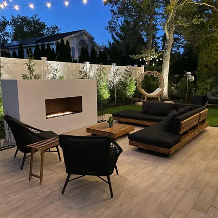 a roof deck with table and chairs with wooden floor and fence