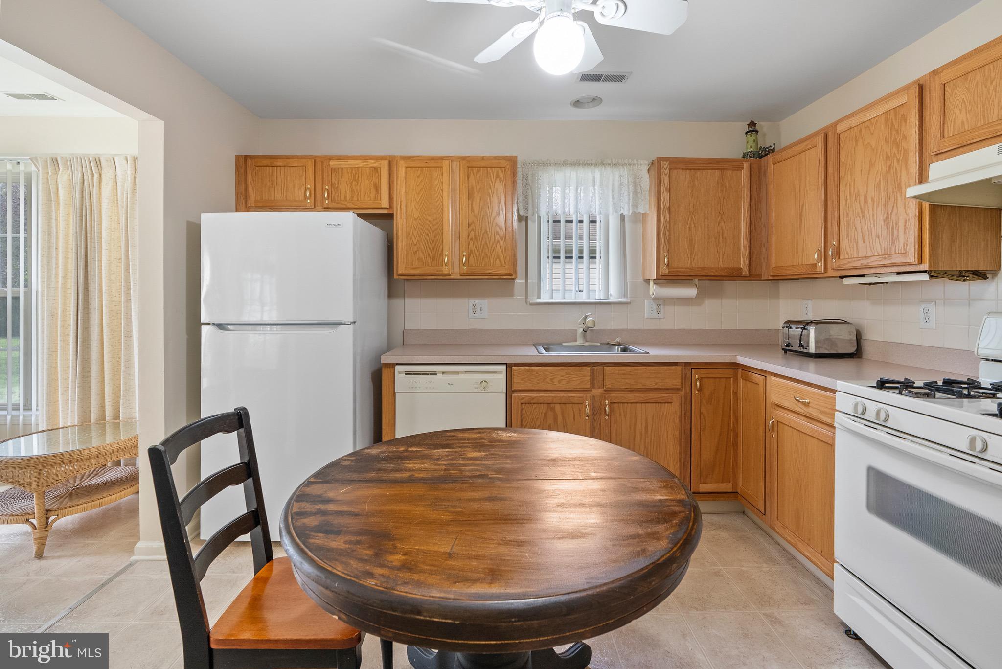 26 Carriage Berlin, NJ 08009 - Photo 9 of 19 a kitchen with stainless steel appliances granite countertop a stove a refrigerator a sink a dining table and chairs with wooden floor
