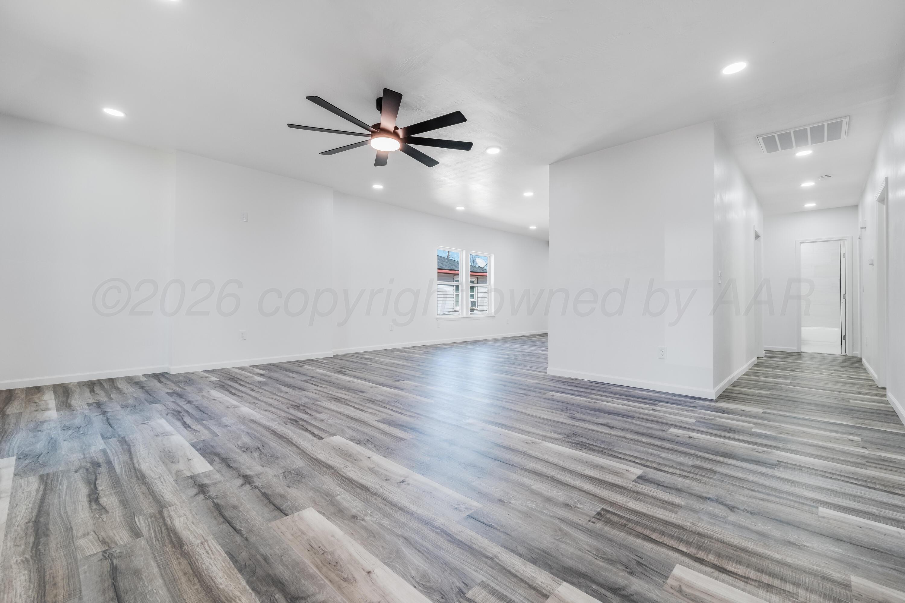 409 South Forest Street Amarillo, TX 79106 - Photo 2 of 18 an empty room with wooden floor a ceiling fan and windows