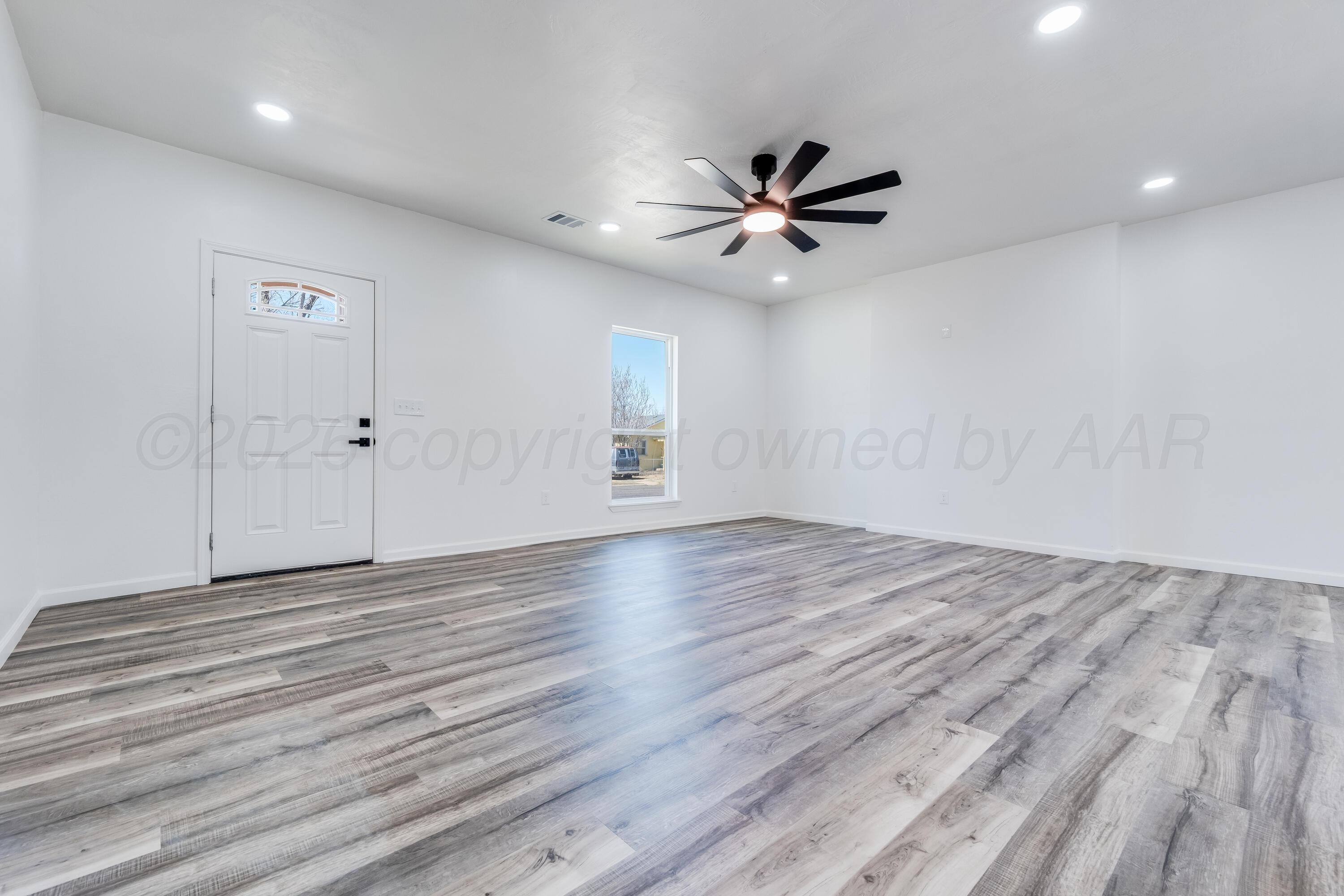 409 South Forest Street Amarillo, TX 79106 - Photo 4 of 18 an empty room with wooden floor fan and windows