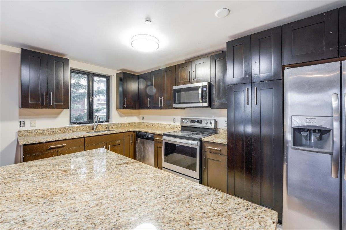 a kitchen with granite countertop stainless steel appliances and a refrigerator