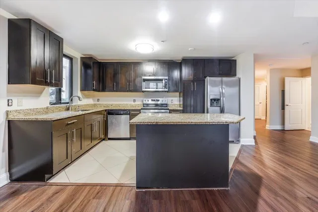 a kitchen with stainless steel appliances granite countertop a sink a stove and a refrigerator