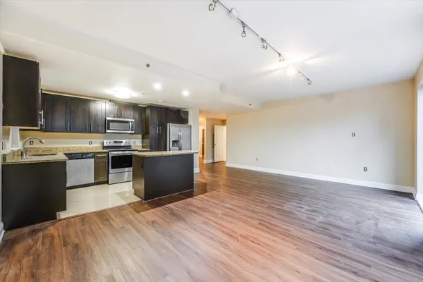 a large kitchen with kitchen island a sink dishwasher a stove and a refrigerator with wooden floor