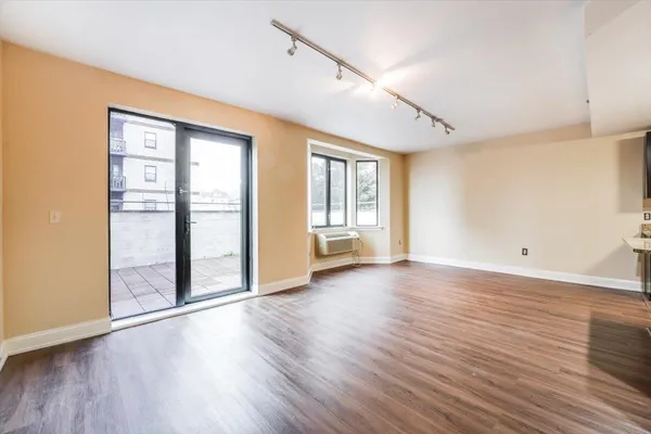 a view of an empty room with wooden floor and a window