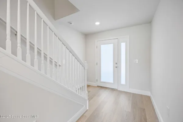 a view of staircase with white walls and white door