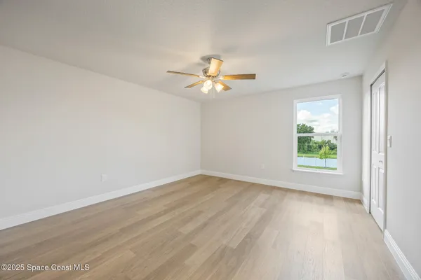 an empty room with wooden floor and a ceiling fan