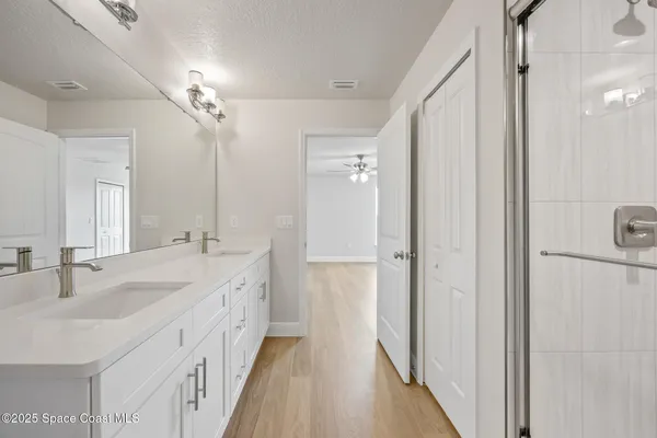 a spacious bathroom with a double vanity sink a mirror and shower