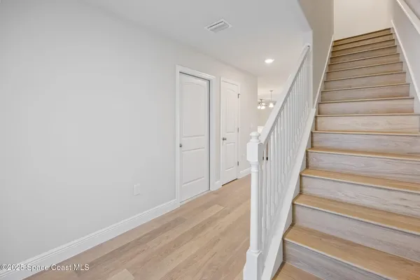 a view of staircase with wooden floor and white walls