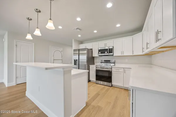 a large kitchen with kitchen island a stove a sink a center island and cabinets