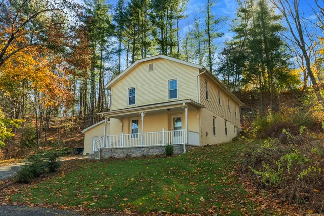 a view of a house with a yard and large trees