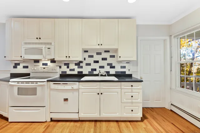 a kitchen with granite countertop white cabinets and white appliances