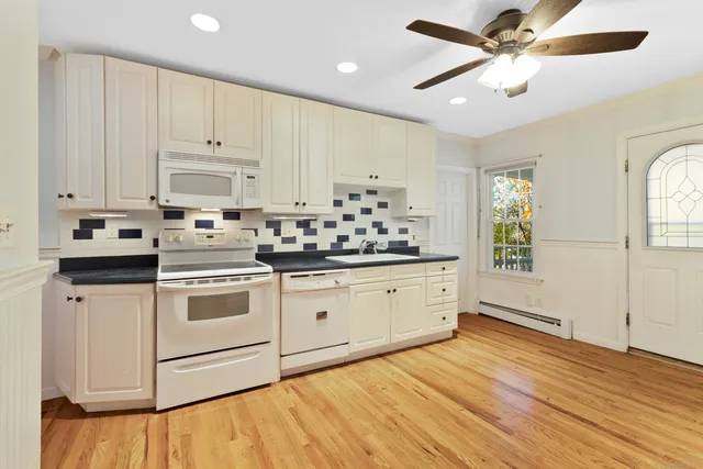 a kitchen with stainless steel appliances granite countertop a stove a sink and white cabinets with wooden floor