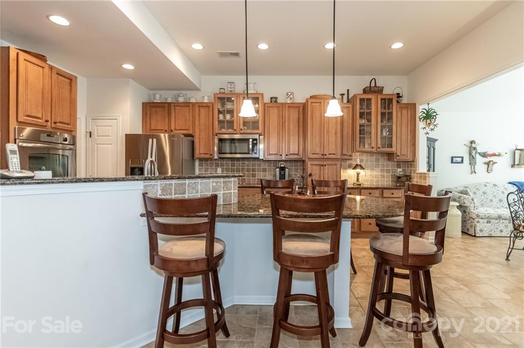 7116 Meyer Road Fort Mill, SC 29715 - Photo 14 of 31 a kitchen with stainless steel appliances kitchen island granite countertop a dining table chairs and a refrigerator