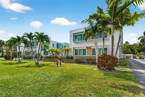 a view of a house with a yard and palm trees