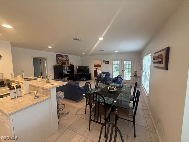 a kitchen with stainless steel appliances a sink a stove a refrigerator cabinets and chairs