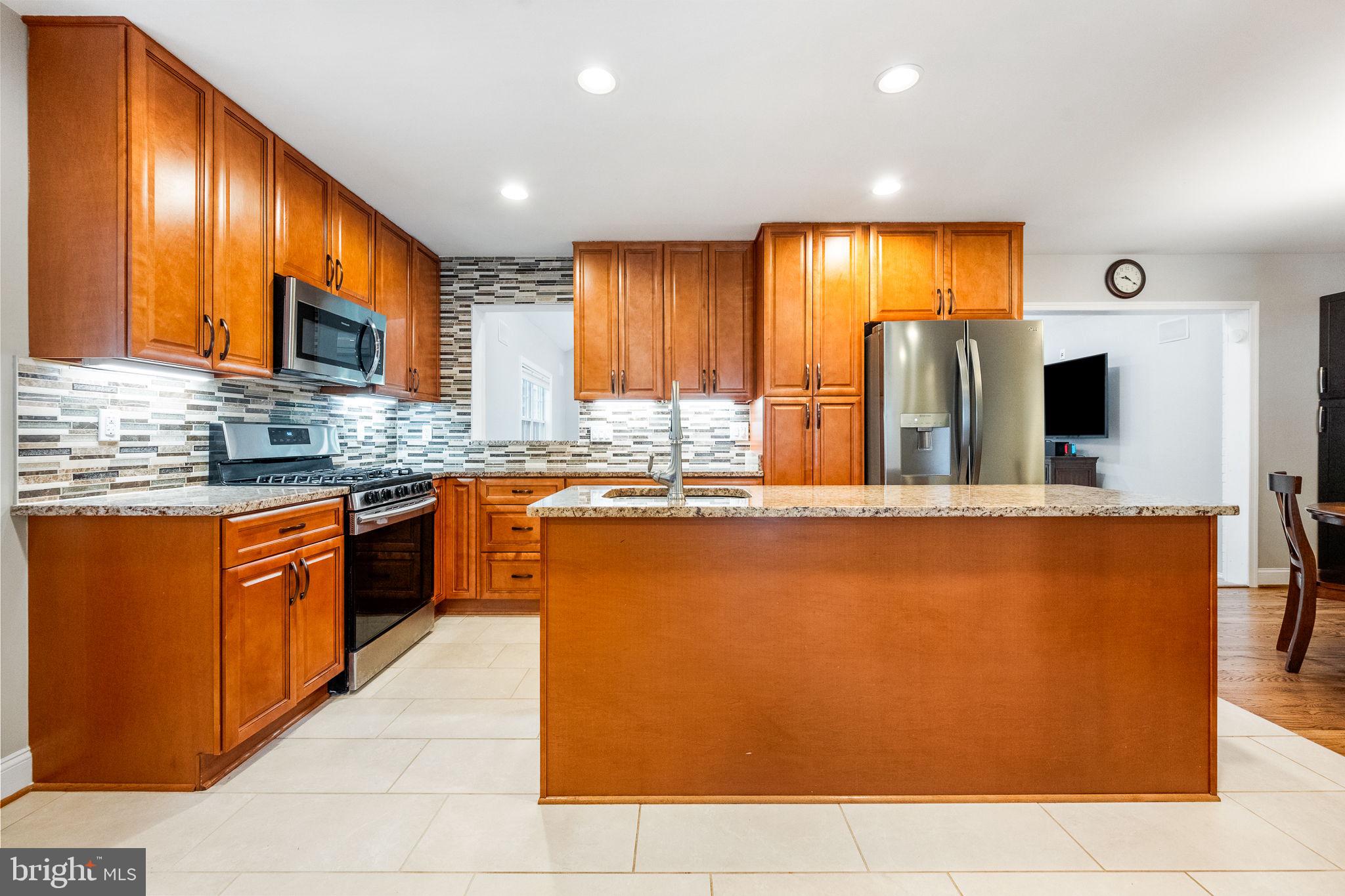 a kitchen with kitchen island granite countertop wooden cabinets a sink a stove and a refrigerator