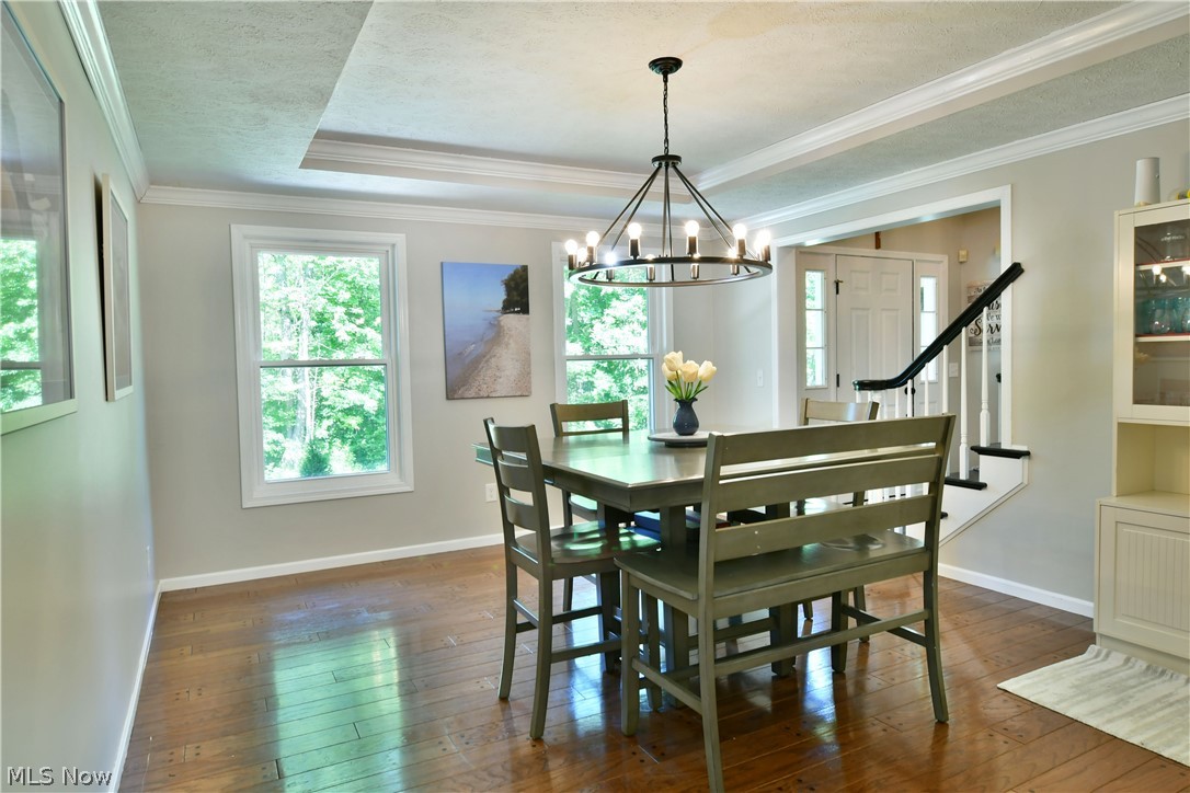 13491 Woodin Road Chardon, OH 44024 - Photo 13 of 35 Dining area featuring crown molding, a textured ceiling, a tray ceiling, dark hardwood / wood-style floors, and a notable chandelier