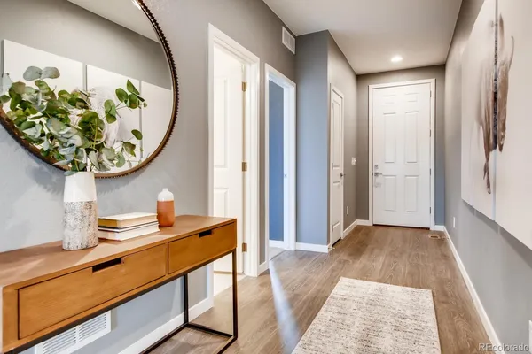 a view of a hallway to a livingroom with wooden floor and a chandelier
