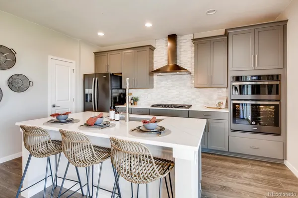 a kitchen with stainless steel appliances granite countertop a dining table chairs refrigerator and cabinets