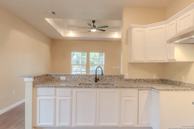 a sink with granite countertop white cabinets and a granite counter top