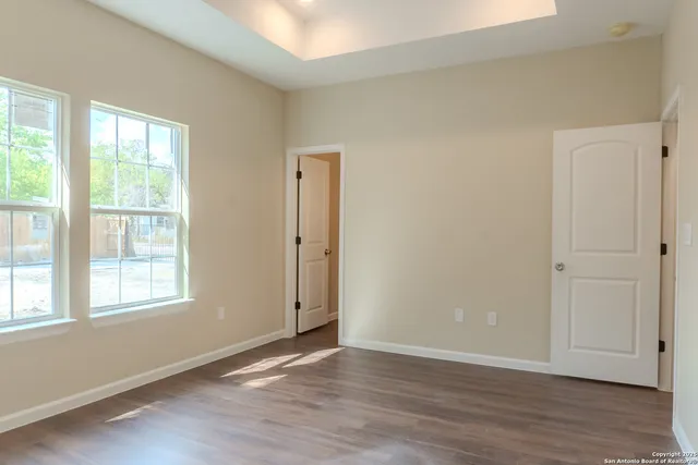 an empty room with wooden floor and windows