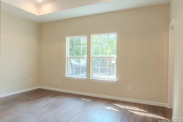 an empty room with wooden floor and windows