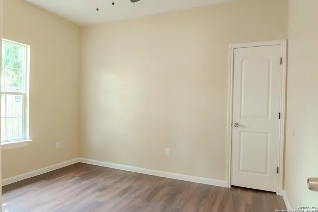 an empty room with wooden floor and window