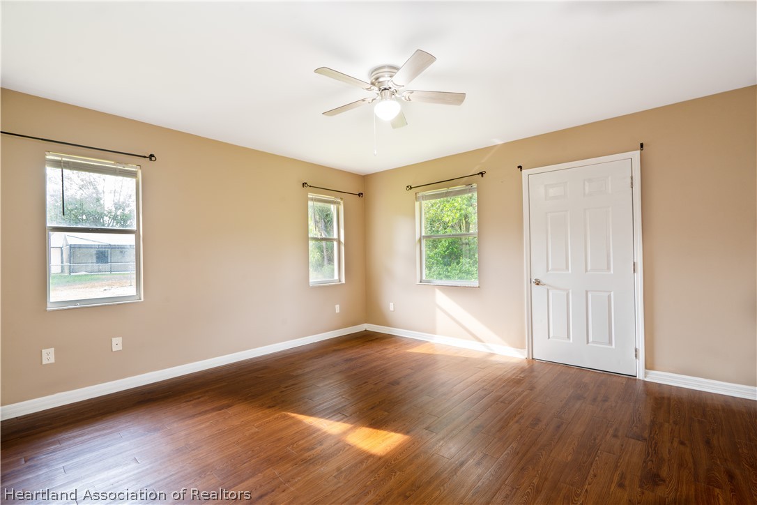 309 Lark Terrace Sebring, FL 33872 - Photo 13 of 32 a view of an empty room with wooden floor and a window