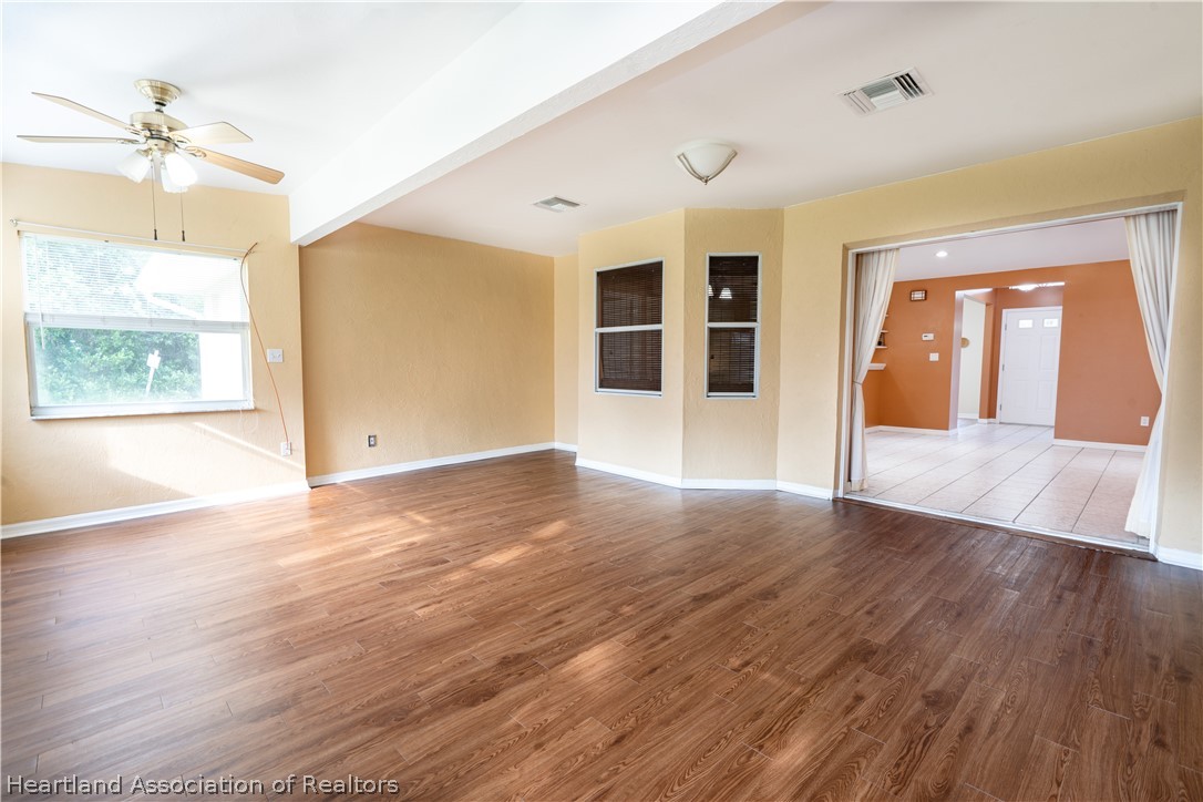 309 Lark Terrace Sebring, FL 33872 - Photo 16 of 32 a view of an empty room with a window and wooden floor