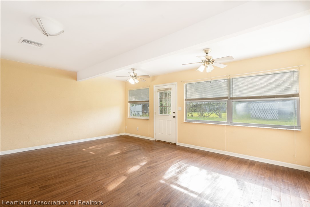 309 Lark Terrace Sebring, FL 33872 - Photo 18 of 32 an empty room with wooden floor and windows