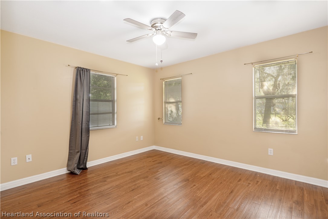 309 Lark Terrace Sebring, FL 33872 - Photo 20 of 32 an empty room with wooden floor chandelier fan and windows