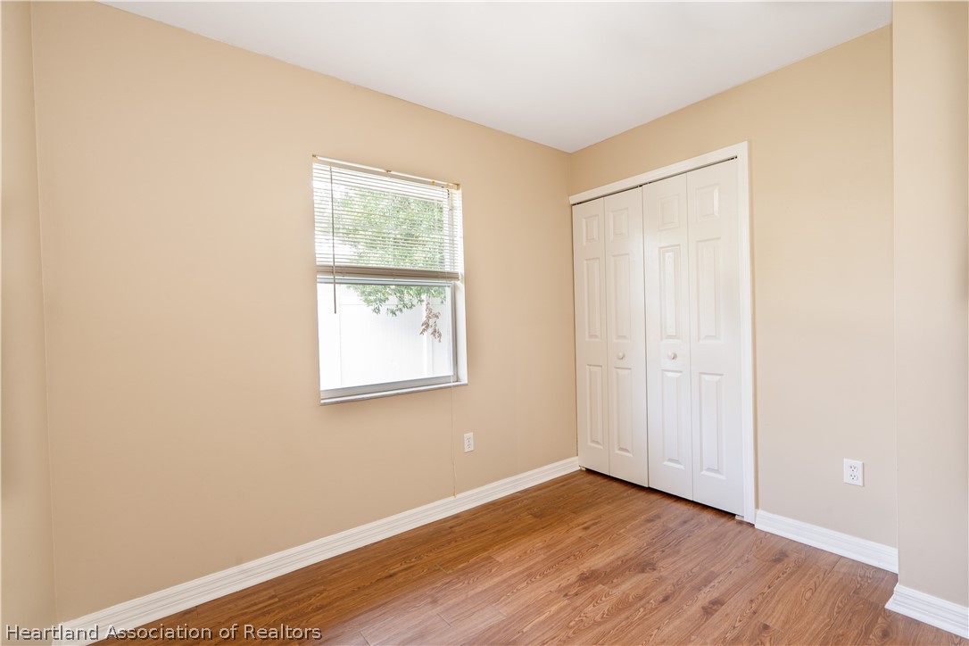 309 Lark Terrace Sebring, FL 33872 - Photo 22 of 32 an empty room with wooden floor and windows