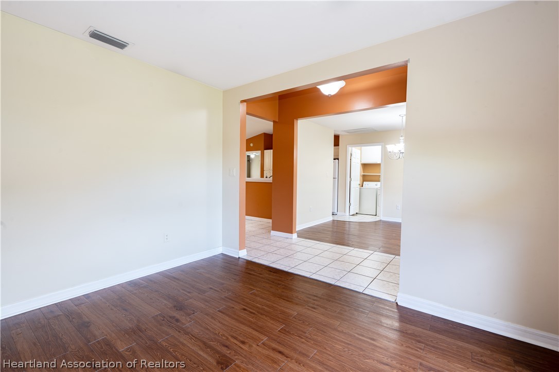 309 Lark Terrace Sebring, FL 33872 - Photo 6 of 32 a view of an empty room with wooden floor and a mirror