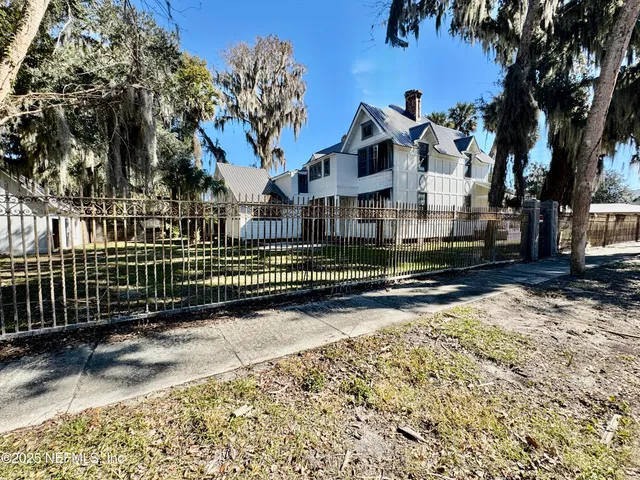 a view of a house with a small yard and wooden fence