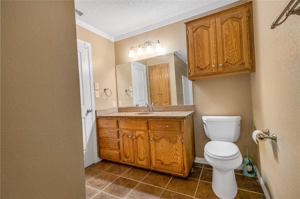 1609 Robin Street Mineola, TX 75773 - Photo 13 of 24 Vanity featuring a light wood-finish cabinet with multiple drawers and doors, a light-toned countertop, and an integrated sink with a chrome faucet