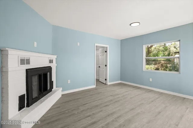 an empty room with windows and fireplace