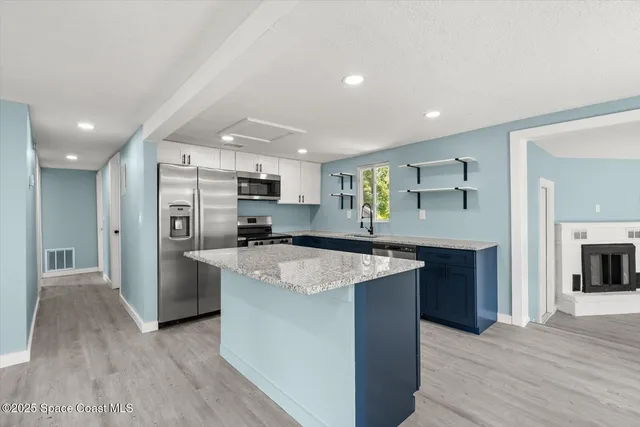 a kitchen with stainless steel appliances granite countertop a refrigerator a sink dishwasher and a oven with wooden floor