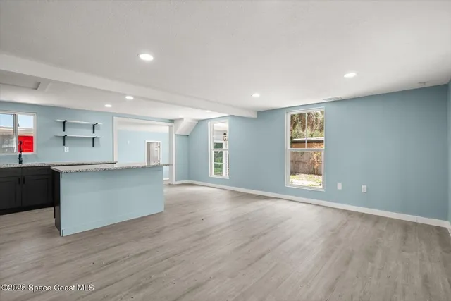 a view of an empty room with wooden floor and windows