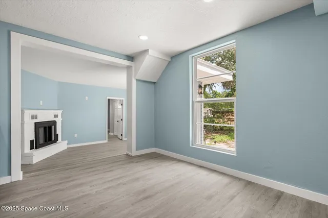 an empty room with windows and fireplace