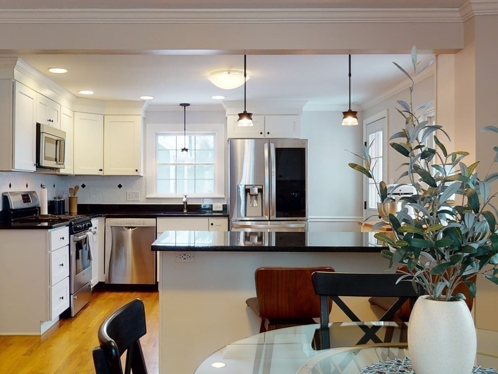 29 Baker Road Arlington, MA 02474 - Photo 18 of 36 a kitchen with stainless steel appliances kitchen island granite countertop a table and chairs in it