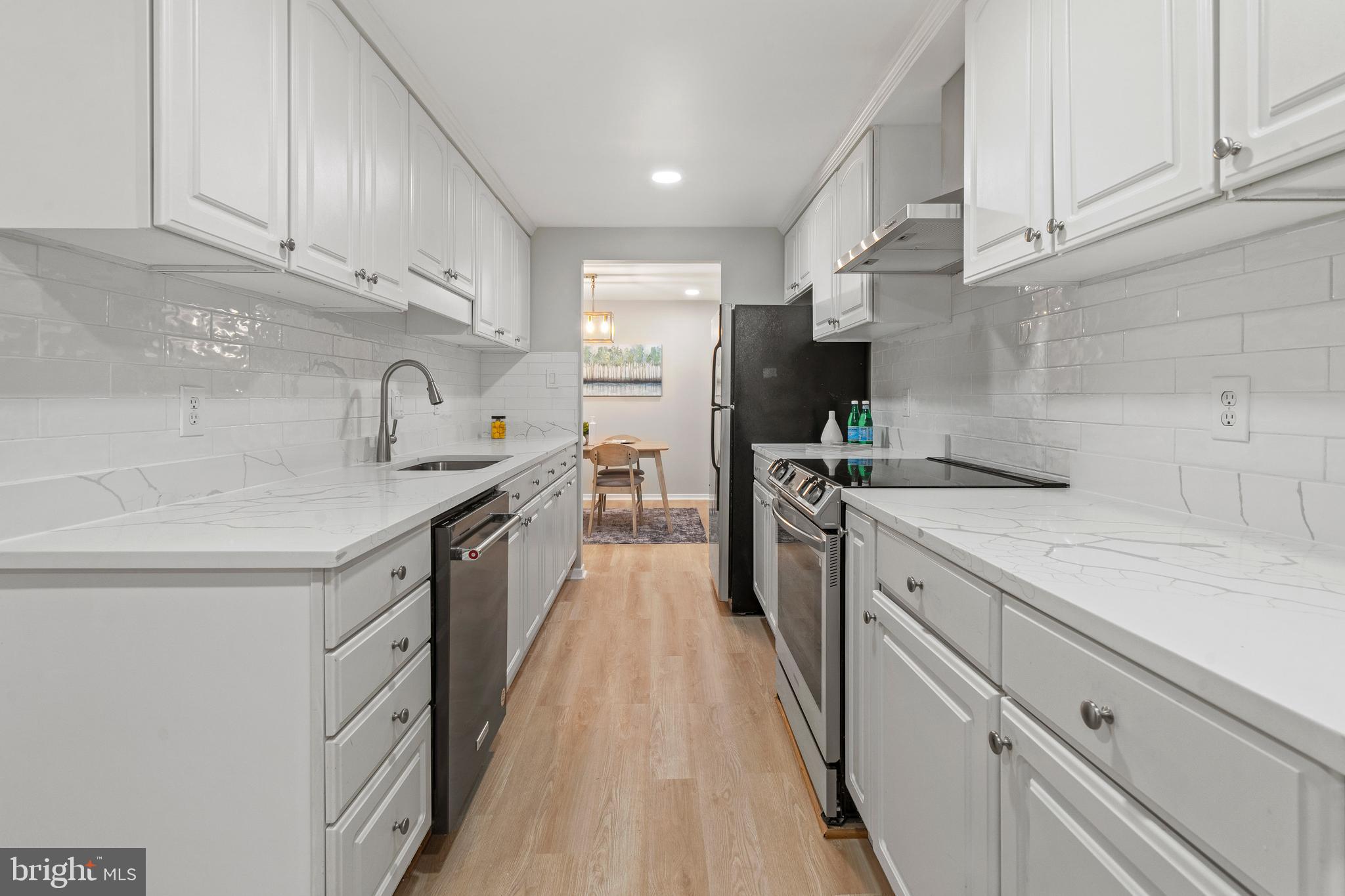 6122 Mantle Road Burke, VA 22015 - Photo 3 of 51 a kitchen with kitchen island white cabinets and white appliances