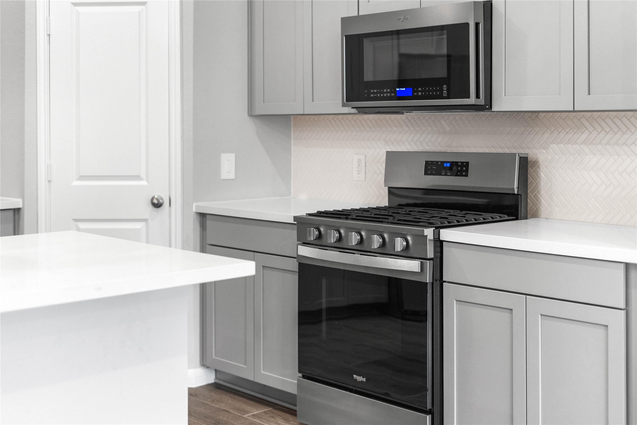 19657 Montgomery Rdg Way Montgomery, TX 77316 - Photo 13 of 49 Showcased here is a Whirlpool gas range, paired with a steam microwave equipped with sensor cooking—all framed by an elegant tile backsplash.